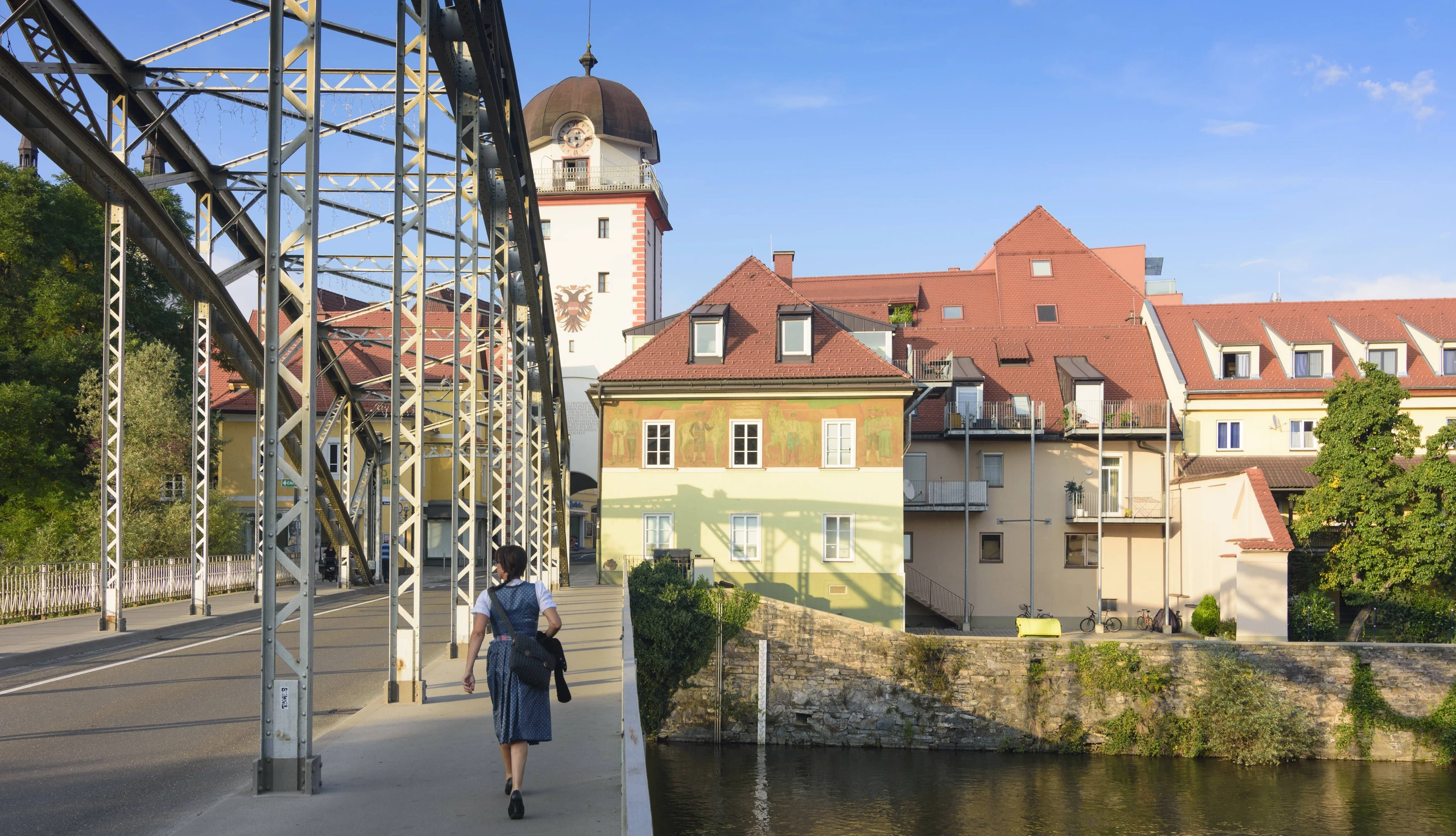 Eine Frau spaziert über die Waasenbrücke in Leoben. Dahinter der Schwammerlturm.