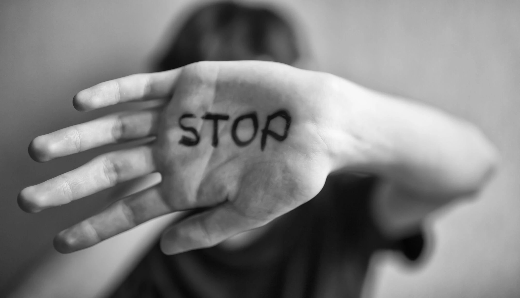 Eine Frau hält eine Hand hoch, auf der das Wort "Stop" geschrieben steht.