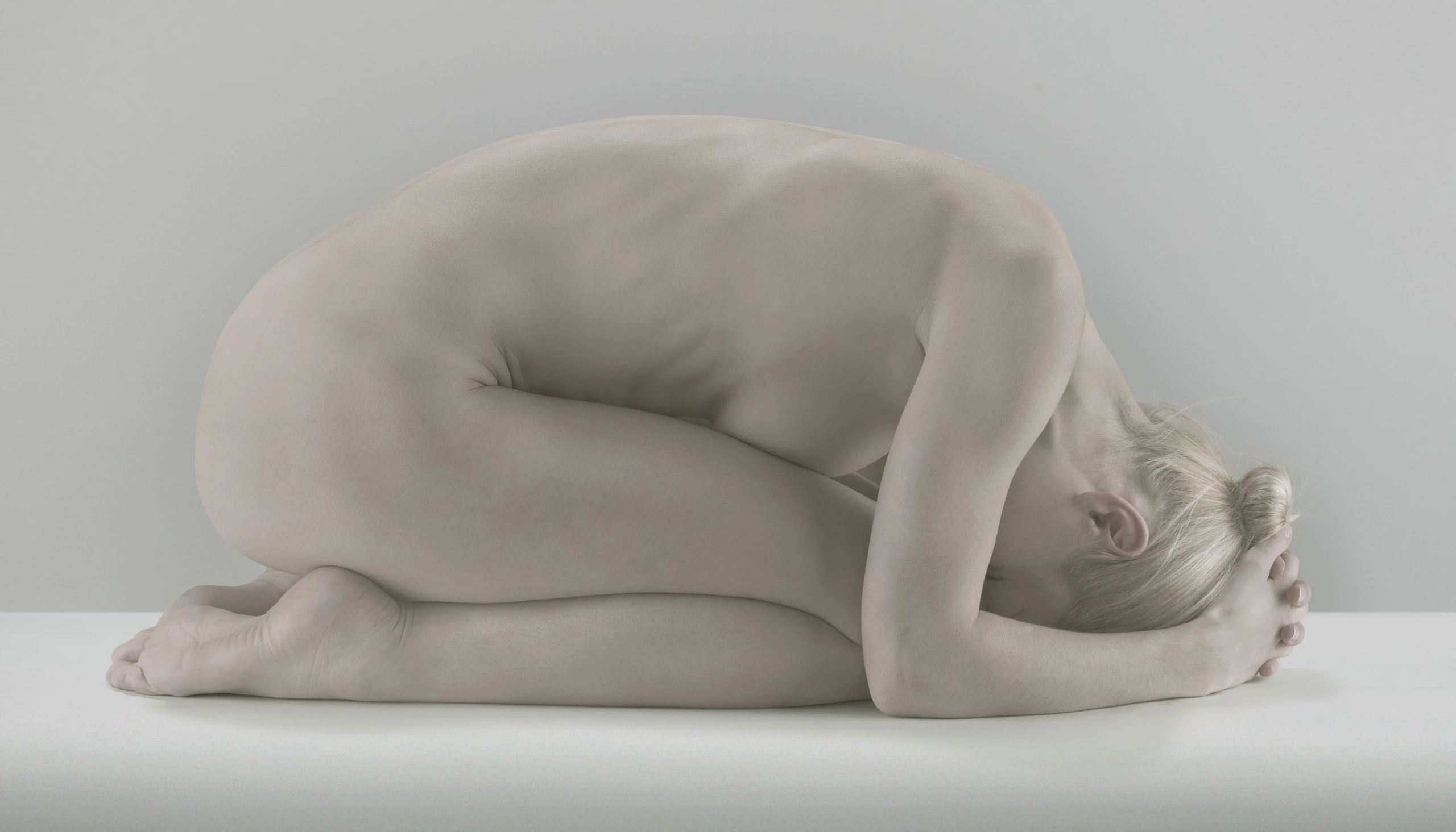 Nackte Frau kauert auf dem Boden