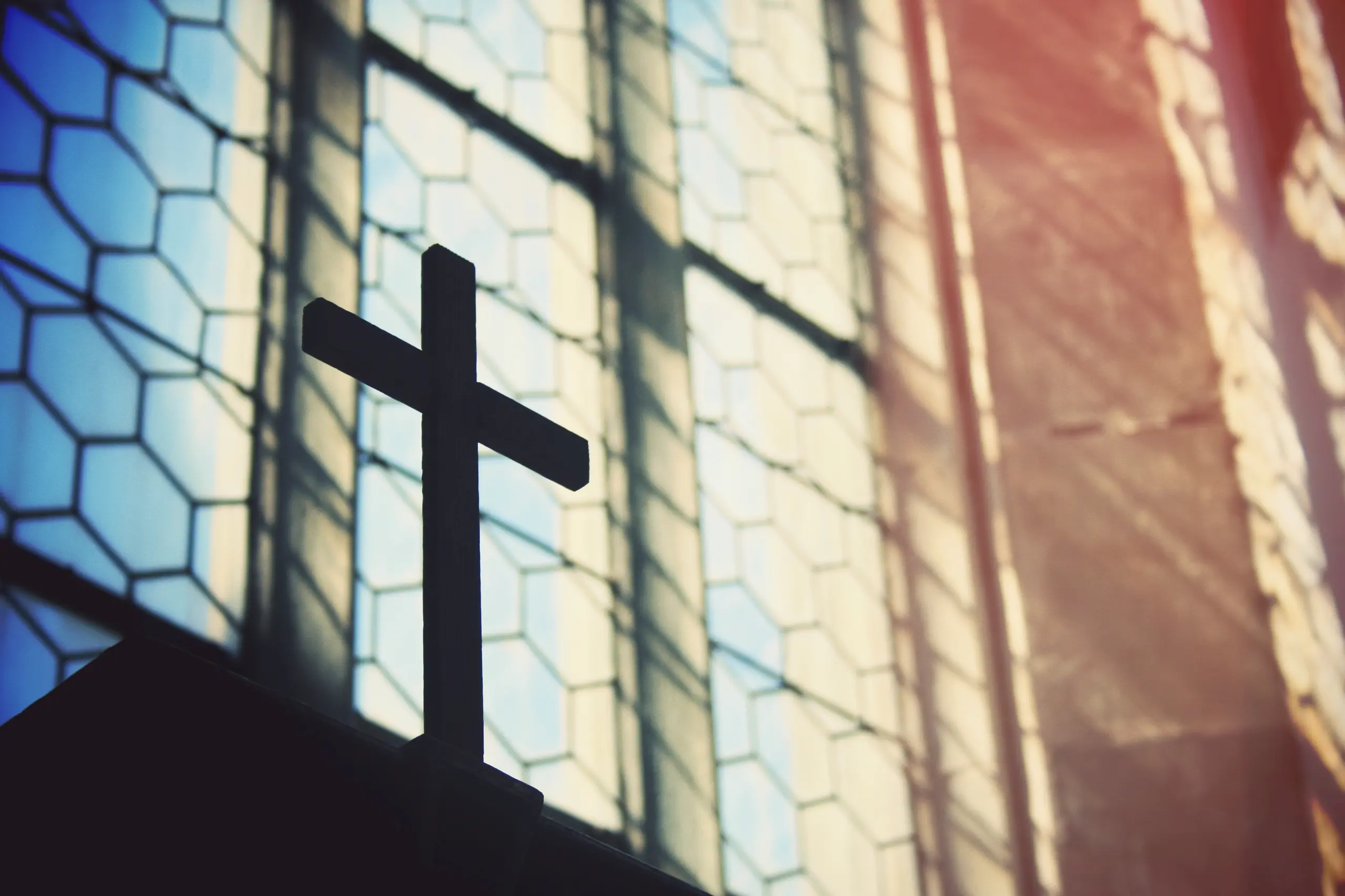 Ein Kreuz in einer Kirche vor einem Fenster.