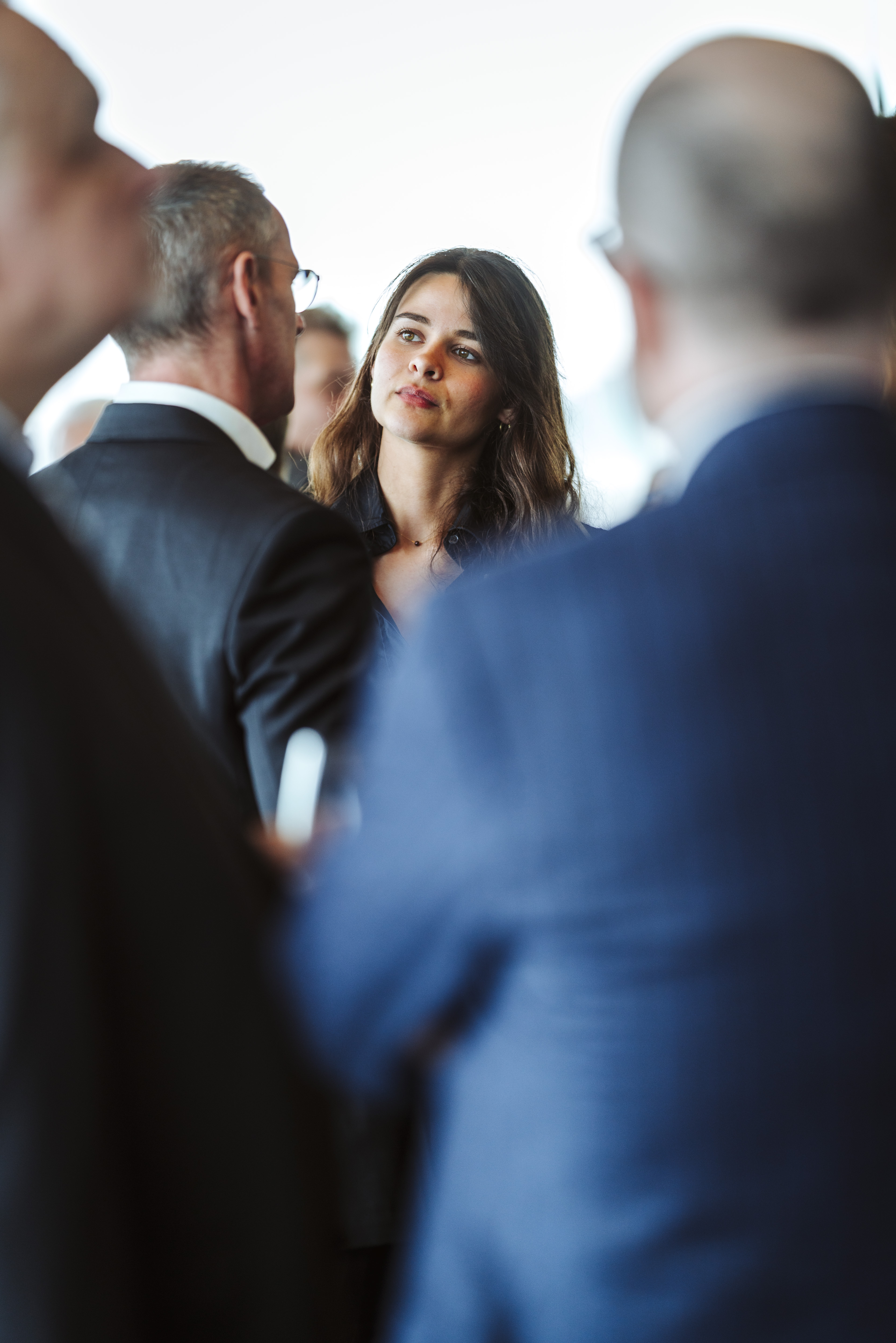 Foto von Nadine Studeny: Junge Frau im Gespräch mit Männern in Businesskleidung. © Nadine Studeny