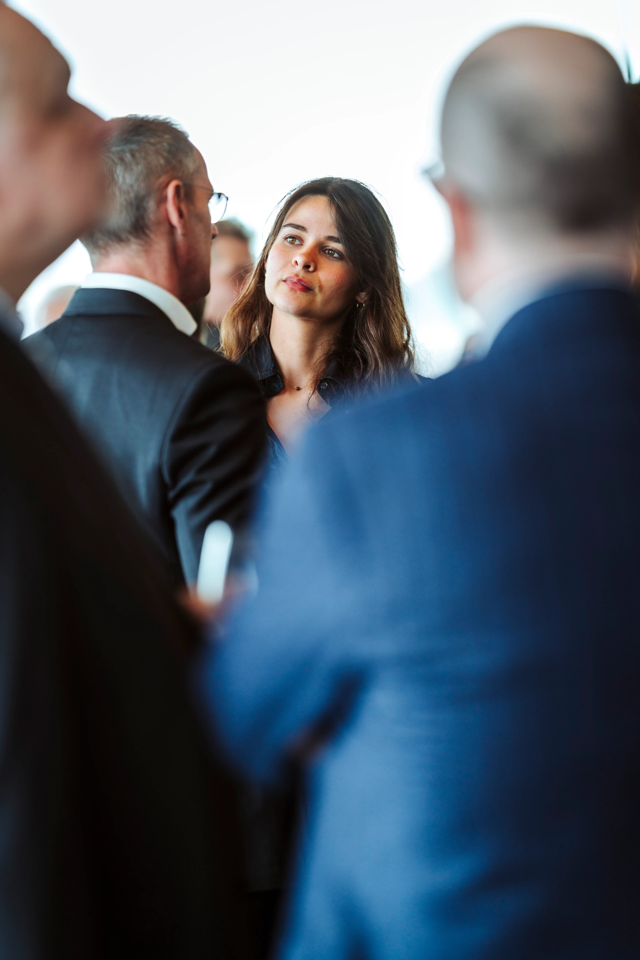 Foto von Nadine Studeny: Junge Frau im Gespräch mit Männern in Businesskleidung. © Nadine Studeny