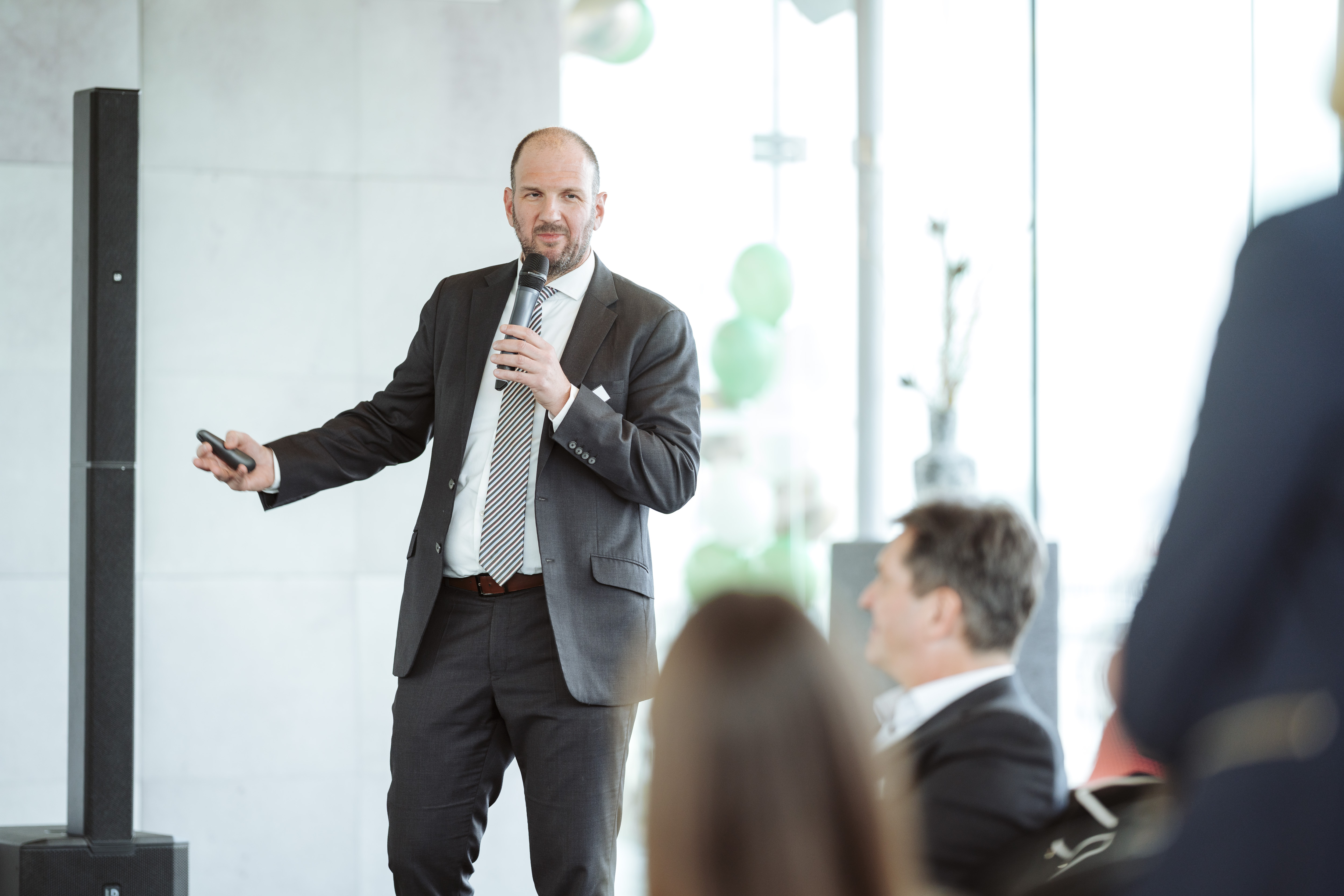 Mann im Anzug hält eine Präsentation mit Mikrofon.  © Nadine Studeny