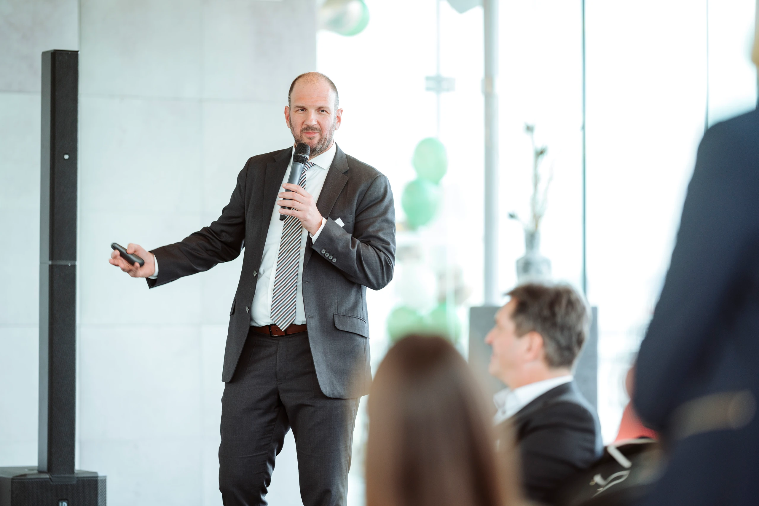Mann im Anzug hält eine Präsentation mit Mikrofon.  © Nadine Studeny
