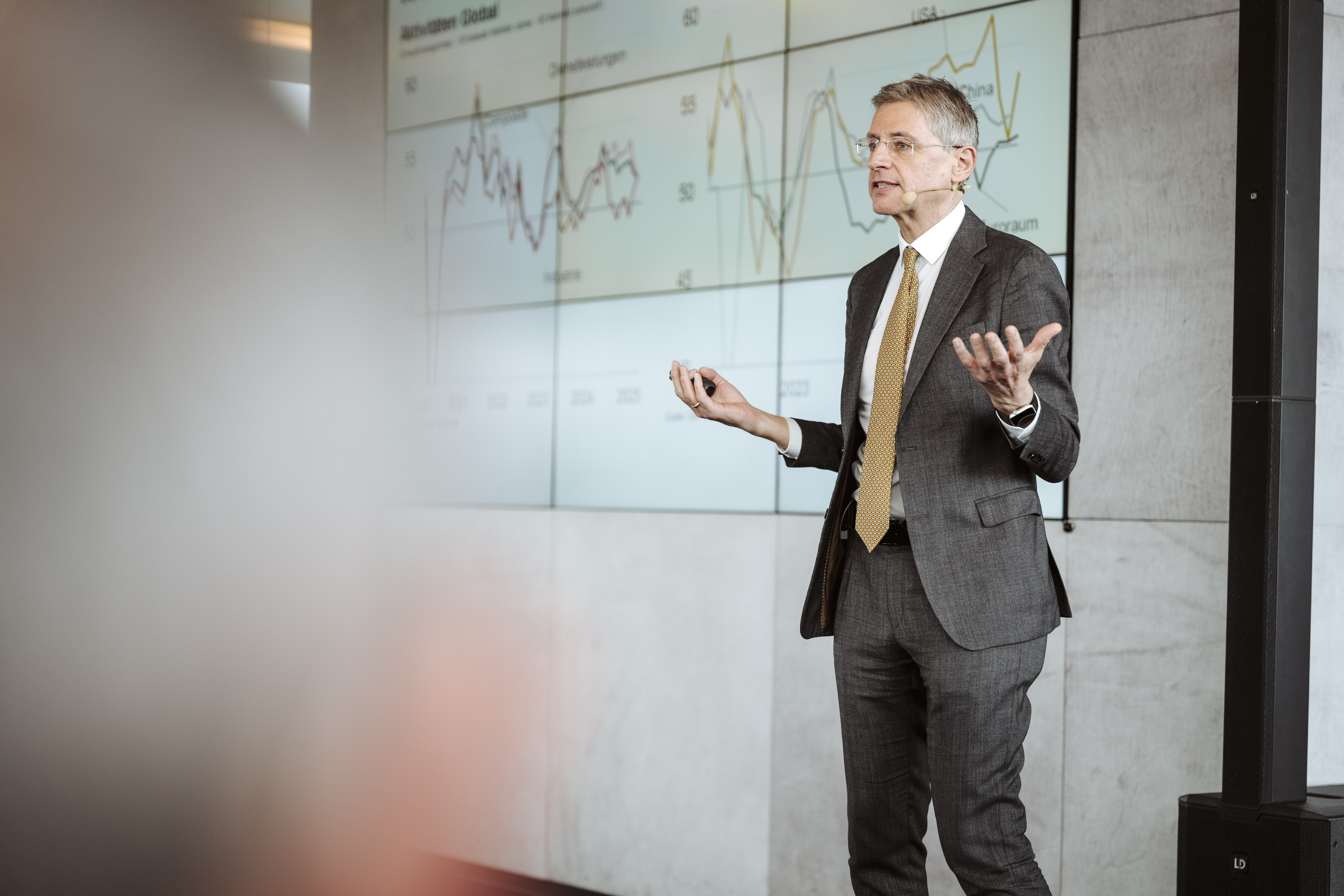 Mann im Anzug hält Präsentation vor Chart-Bildschirm. © Nadine Studeny