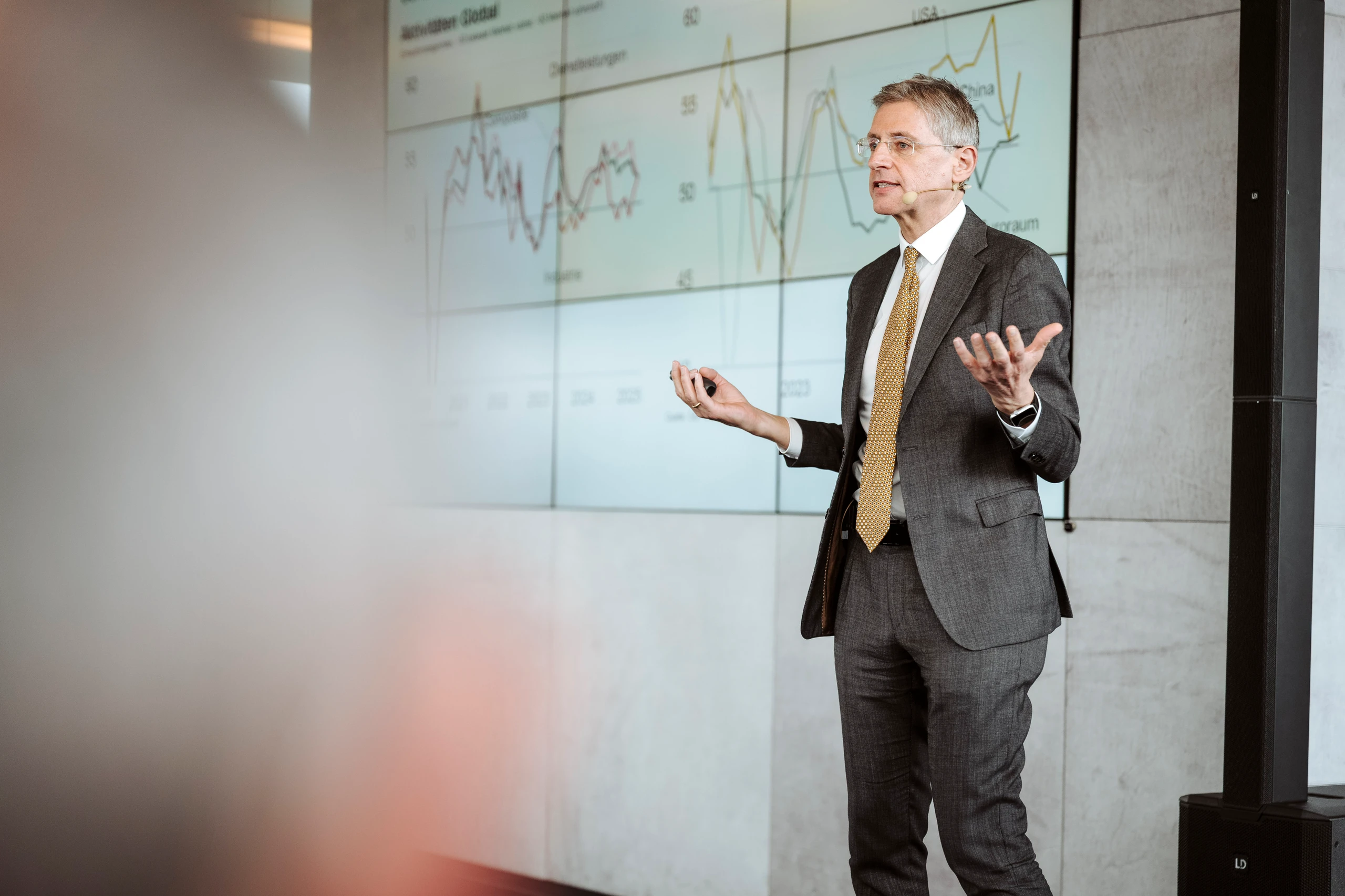 Mann im Anzug hält Präsentation vor Chart-Bildschirm. © Nadine Studeny