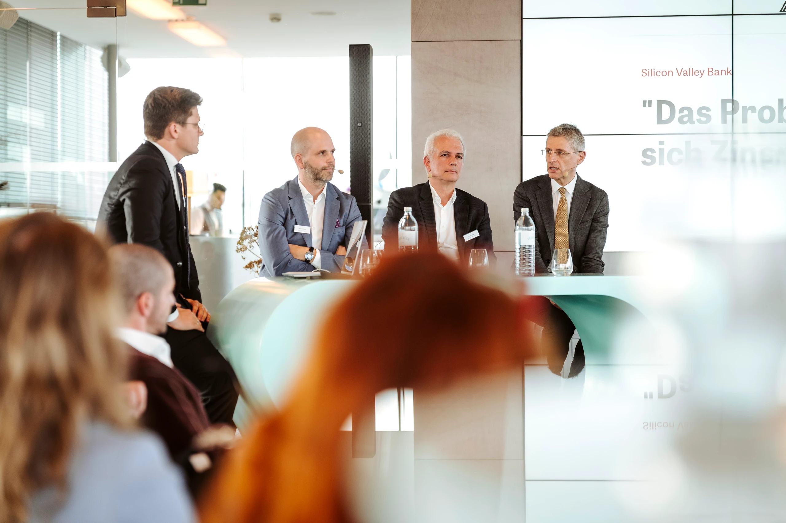 Vier Männer bei einer Podiumsdiskussion mit Silicon Valley Bank Logo im Hintergrund. Foto von Nadine Studeny.
