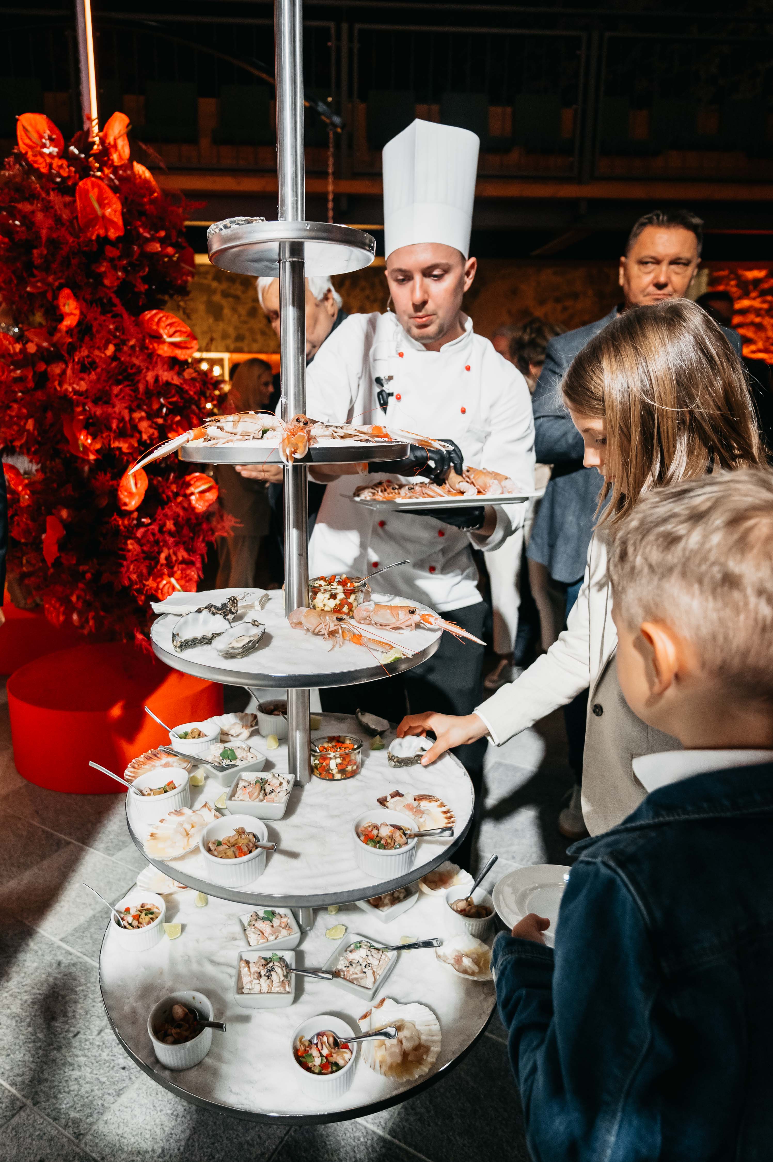 Koch präsentiert Meeresfrüchtegerichte auf mehrstöckigem Tablett.  Professionelles Foto.