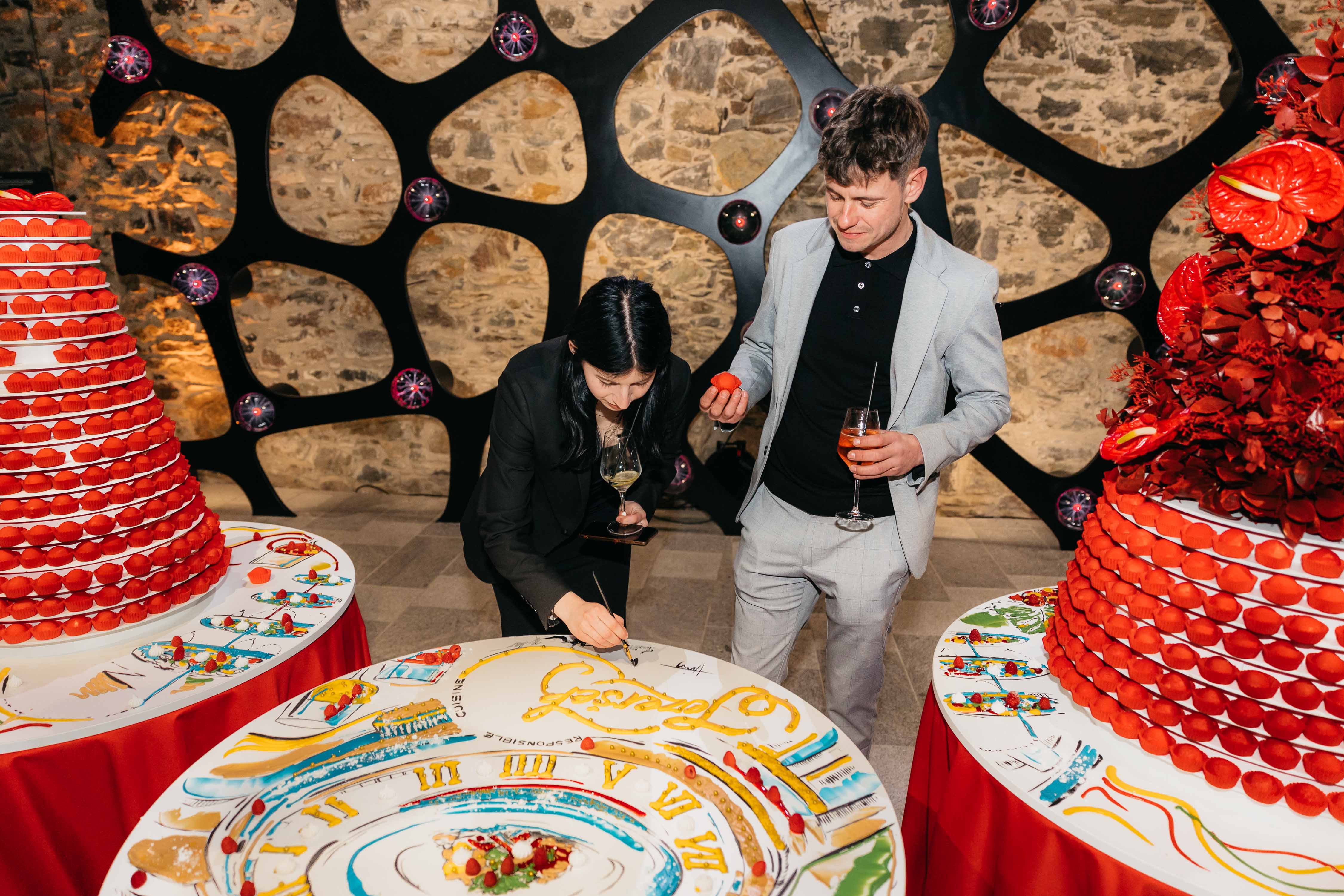 Elegant gedeckte Tische mit handbemalten Motiven & roten Cupcake-Türmen. Stilvolle & kreative Tischdeko.