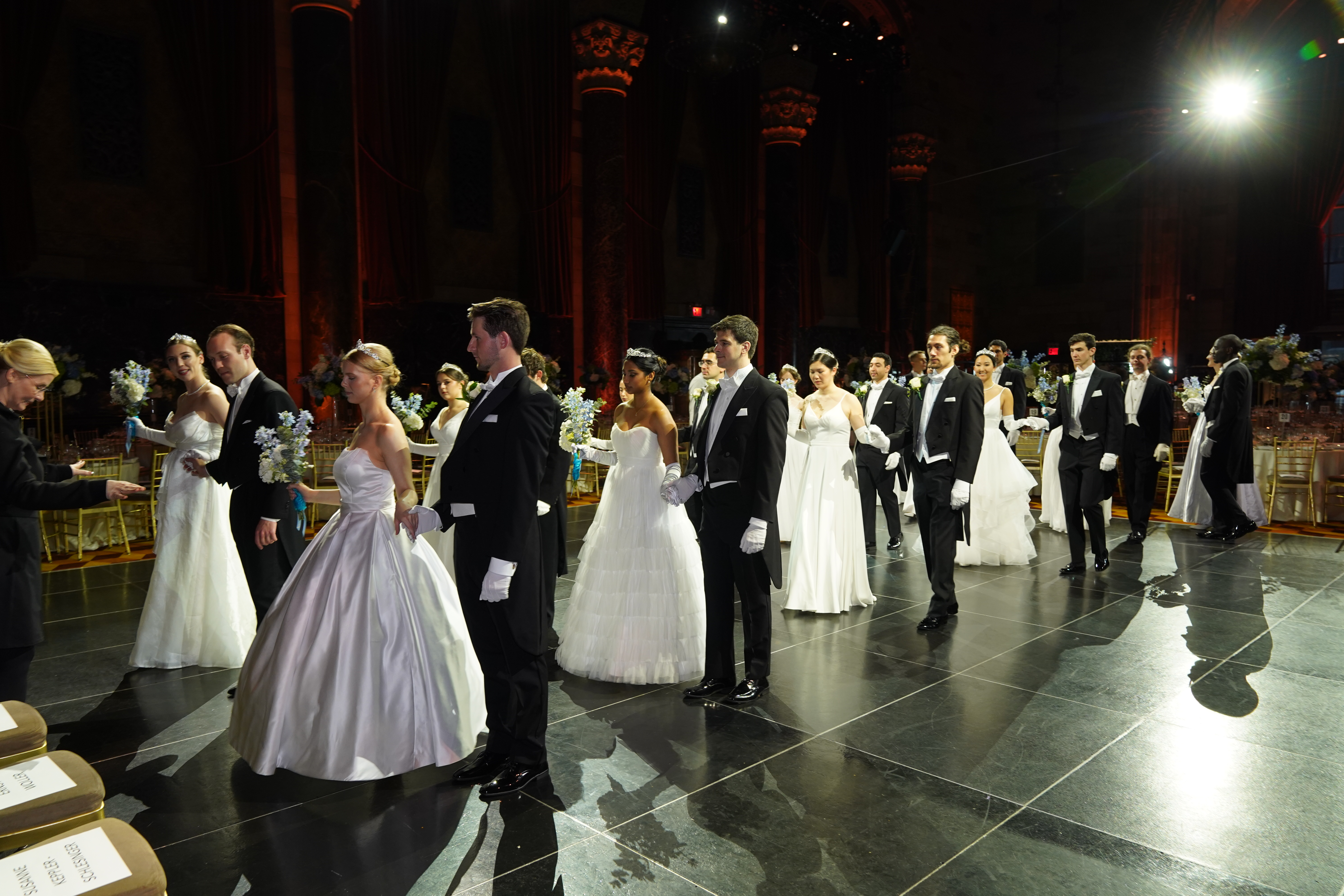 Elegante Paare walzen in einem prächtigen Ballsaal. Frauen in weißen Ballkleidern, Männer in Smokings.
