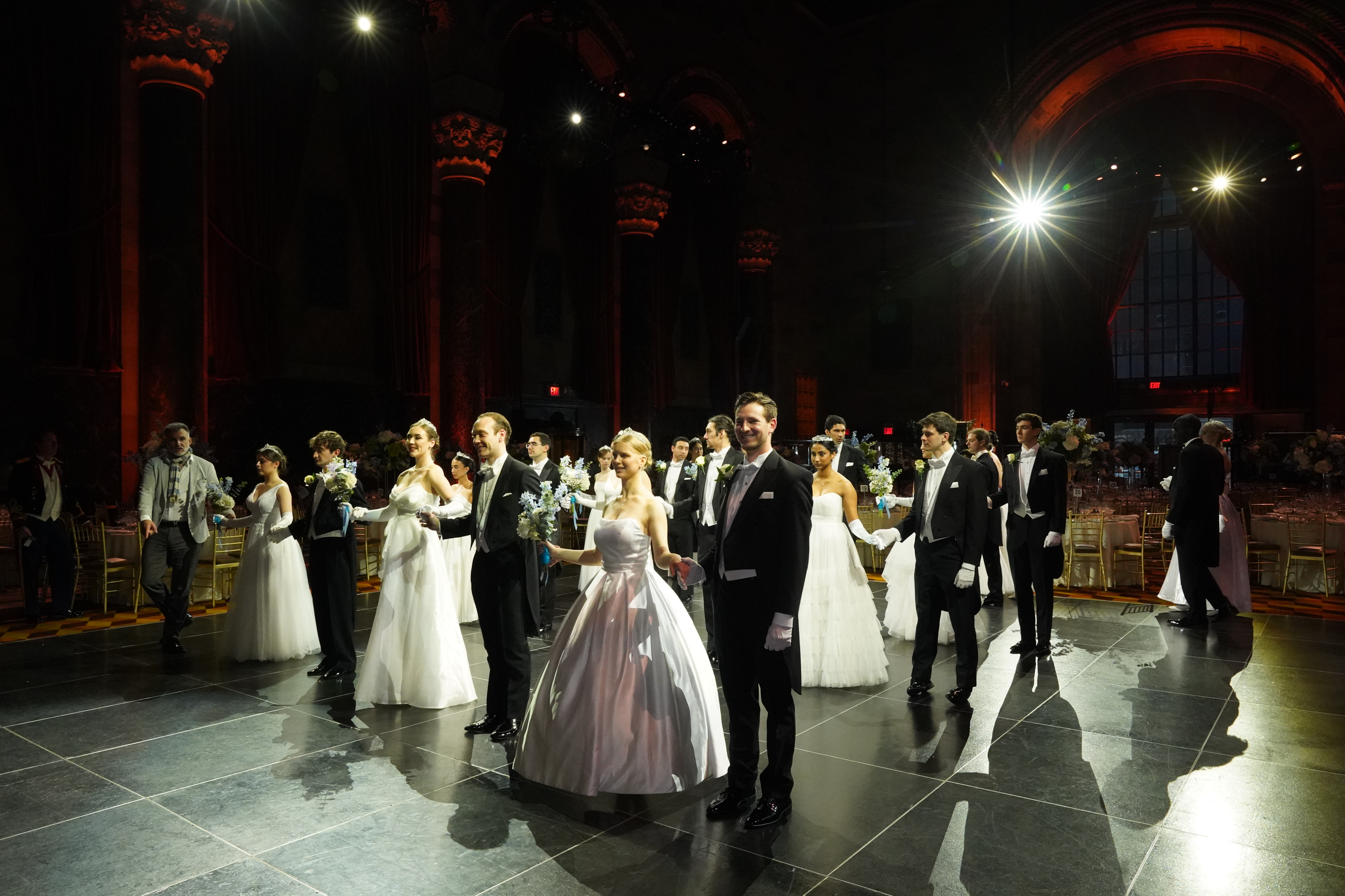 Elegant gekleidete Paare walzern in einem prächtigen Ballsaal. Festliche Atmosphäre.