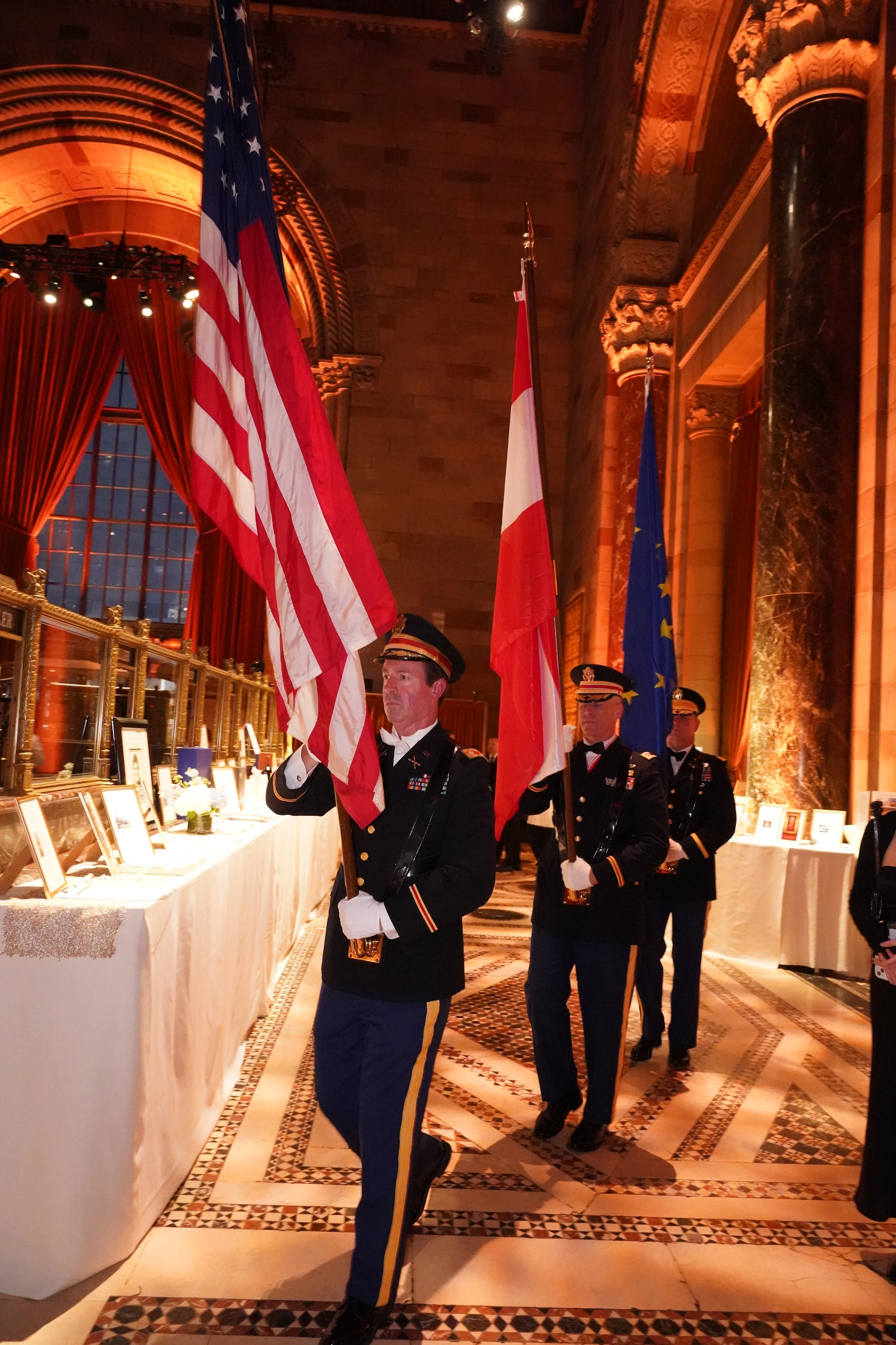Soldaten präsentieren US- und EU-Flaggen bei einer Zeremonie in einem prächtigen Saal.