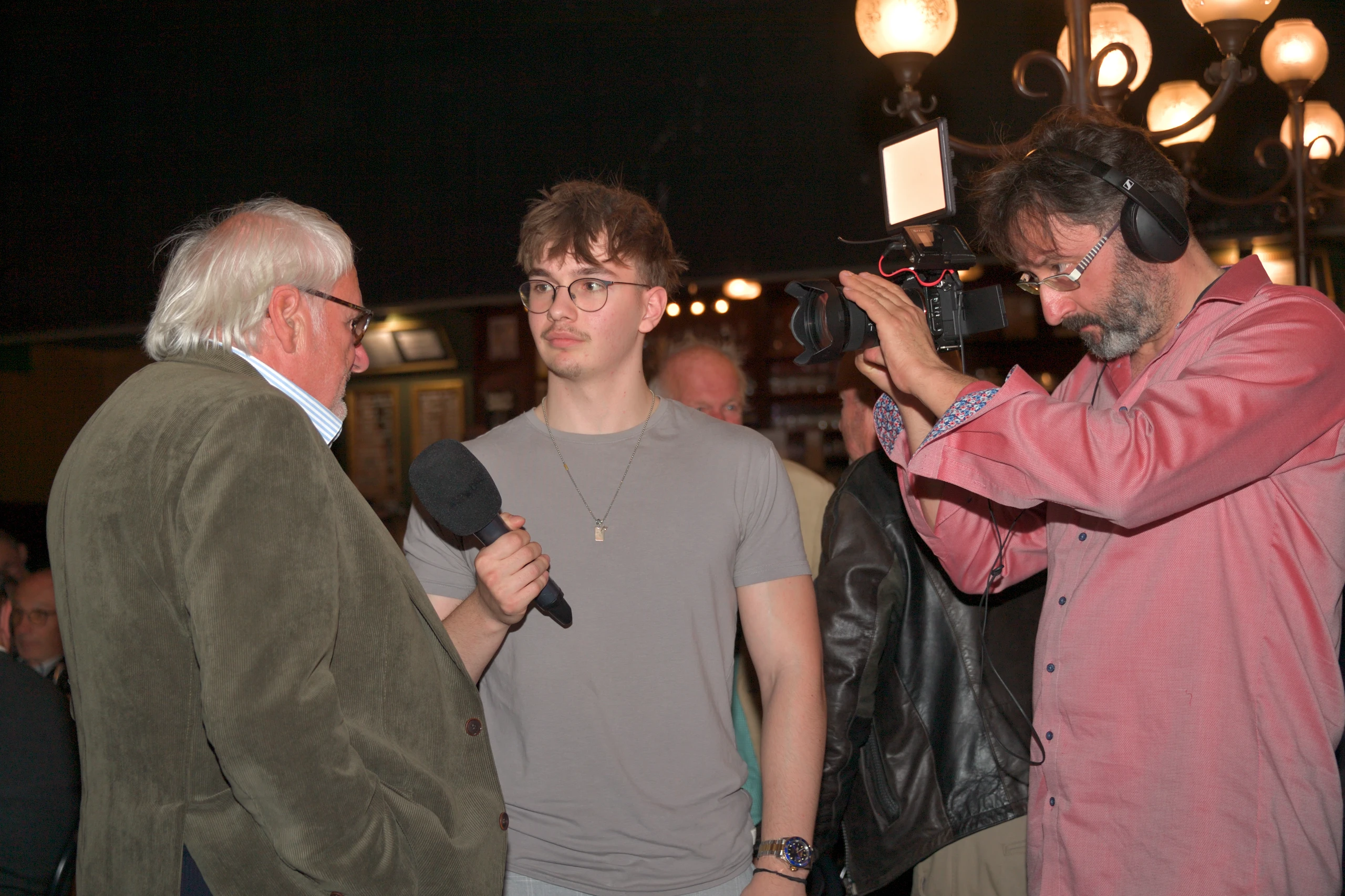 Interviewsituation: Älterer Mann wird interviewt, Kameramann filmt mit professioneller Kamera. Nikon D5.