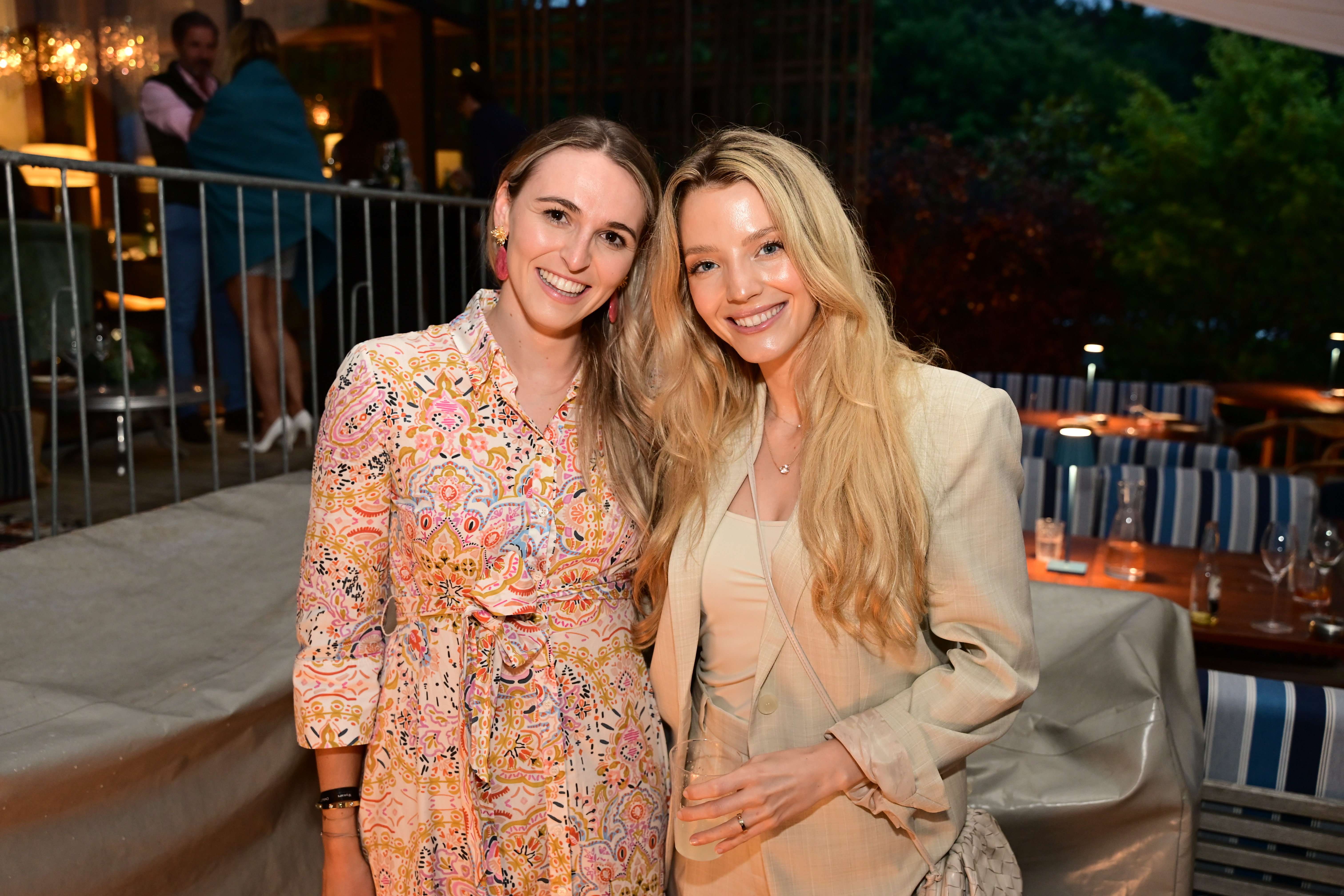Zwei Frauen in eleganten Outfits posieren auf einer Outdoor-Veranstaltung. Nikon Z6_3 Aufnahme.