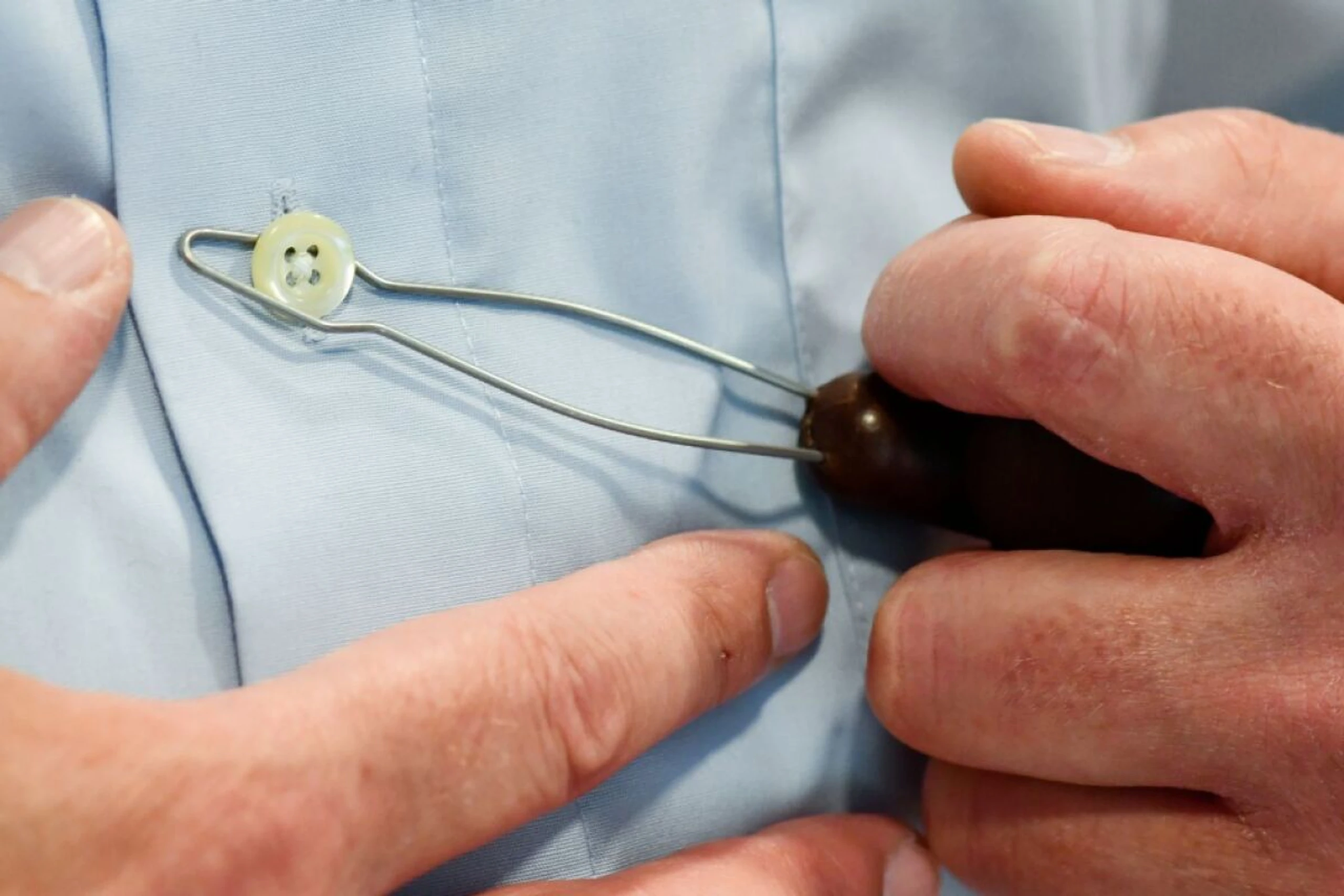 Knöpfhilfe erleichtert es Parkinson-Erkrankten, das Hemd zu schließen