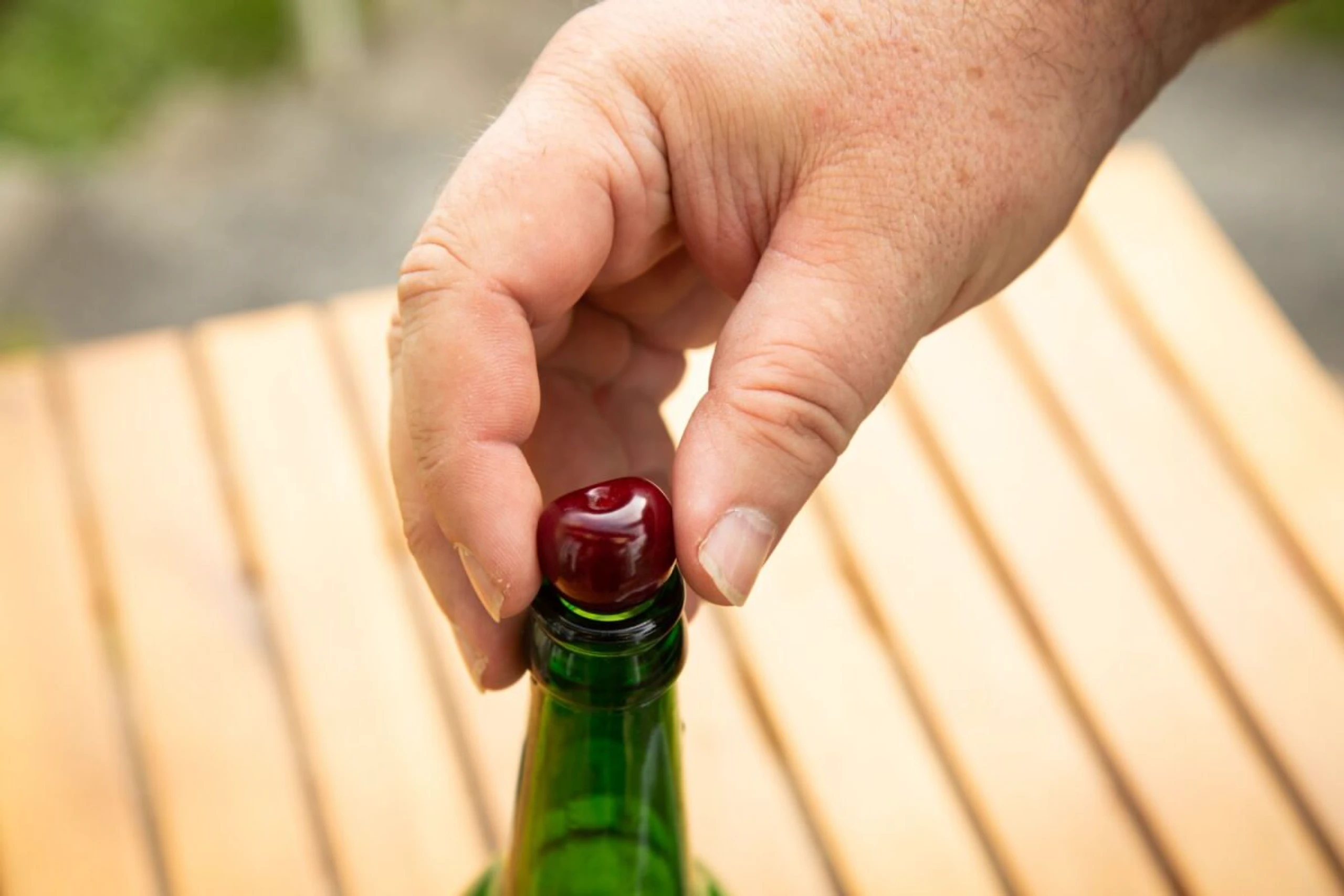 Eine Kirsche auf der Öffnung einer leeren Glasflasche platzieren