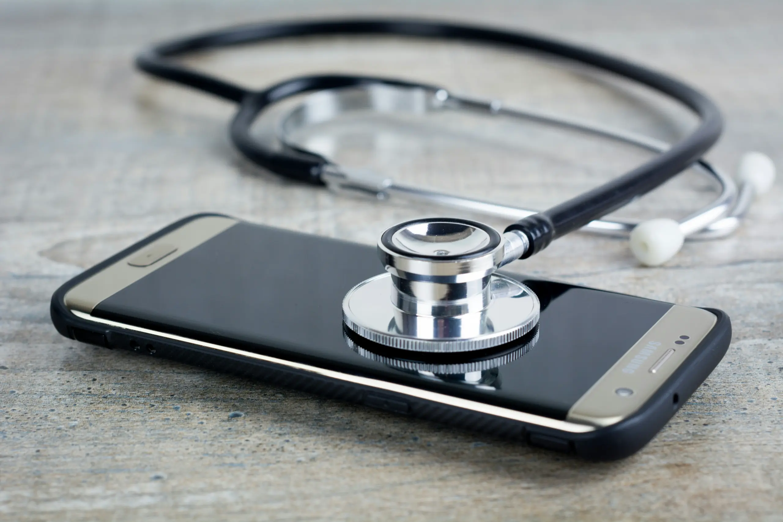 Smartphone mit Stethoskop als Symbol für telefonische Gesundheitsberatung