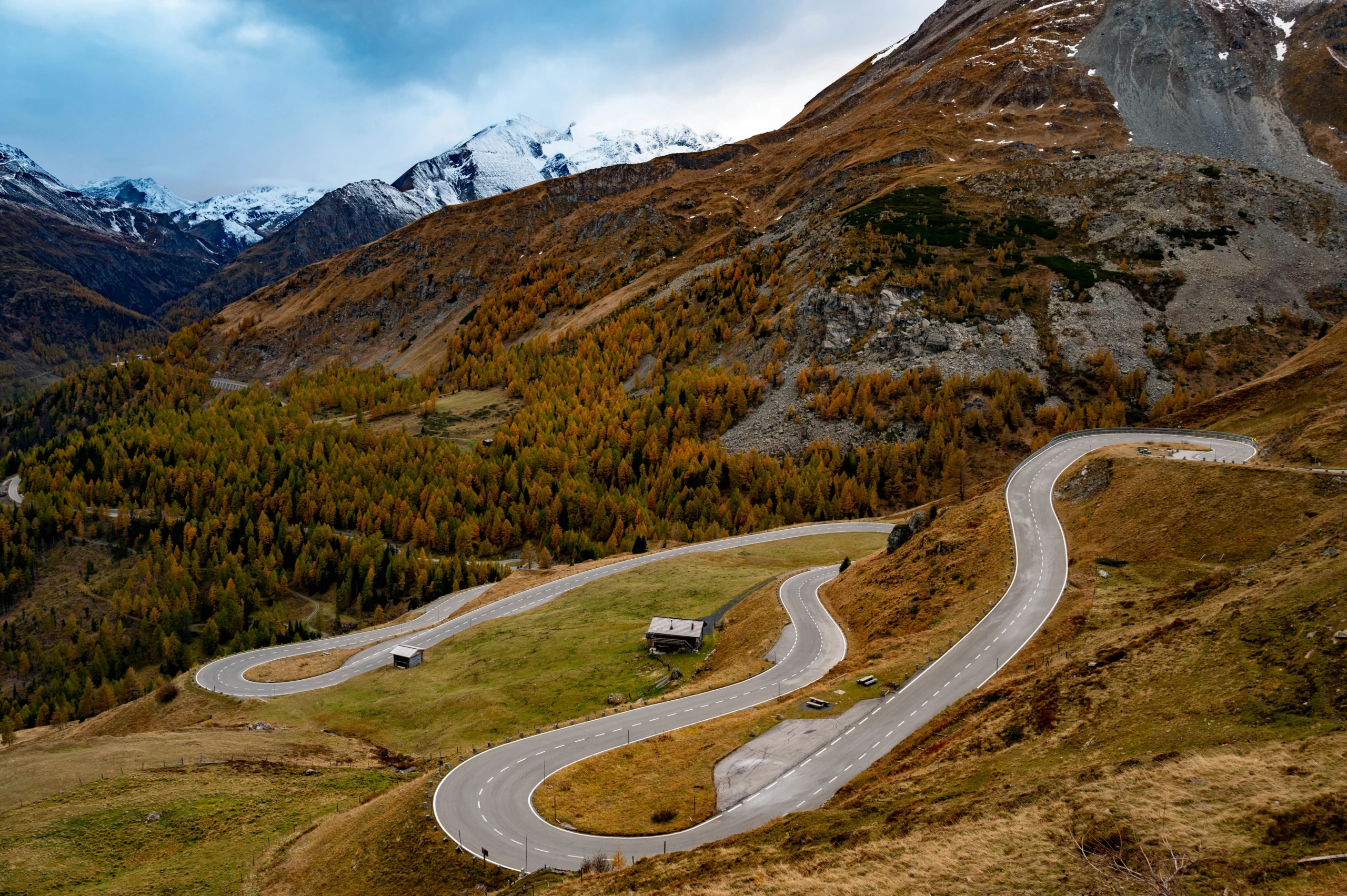 Kurvige Bergstraße im Herbst vor schneebedeckten Gipfeln im Großglocknergebiet